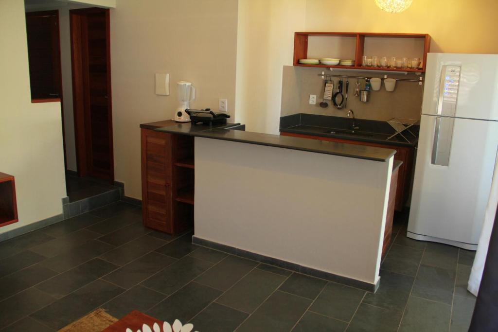 a kitchen with a counter and a white refrigerator at Flor da Mata in Pipa