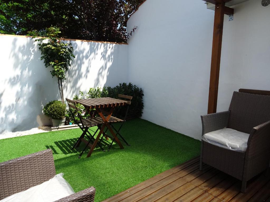 un patio con prato verde, tavolo e sedie di Belle petite maison pour des vacances en duo sur l'île de Noirmoutier a La Guérinière