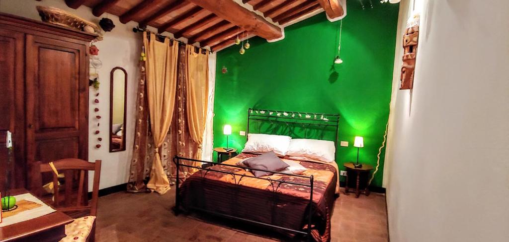 Dormitorio verde con cama con pared verde en B&B Le Undici Lune, en San Gimignano