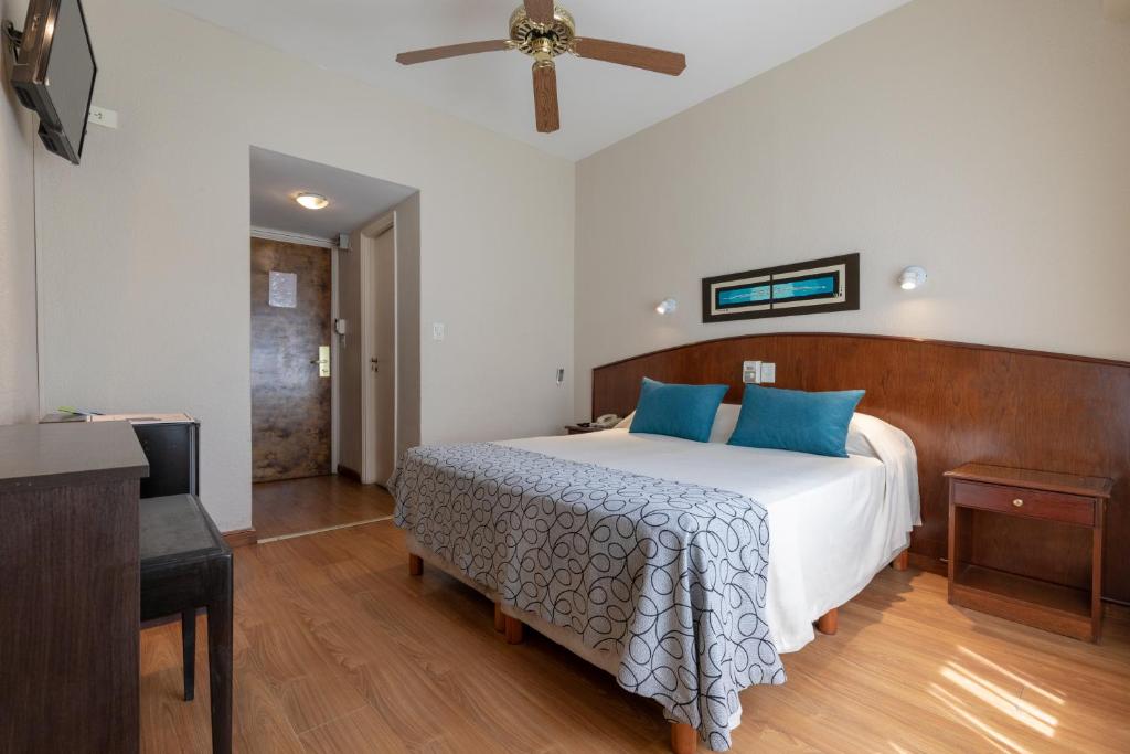 a bedroom with a large bed with blue pillows at Hotel Rivoli in Mar del Plata