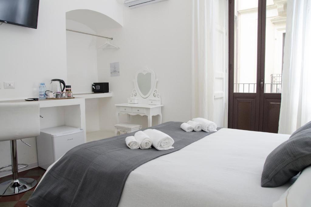 a white bedroom with a bed with towels on it at Sleep Inn Catania rooms - Affittacamere in Catania