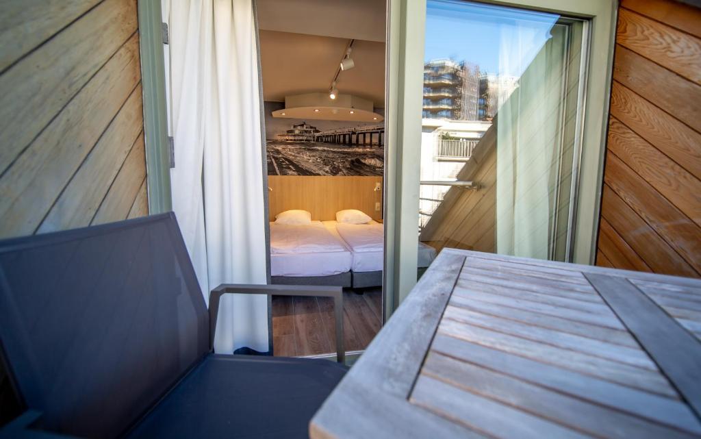 Habitación con balcón, cama y mesa. en Hotel Paradisio by WP Hotels en Blankenberge