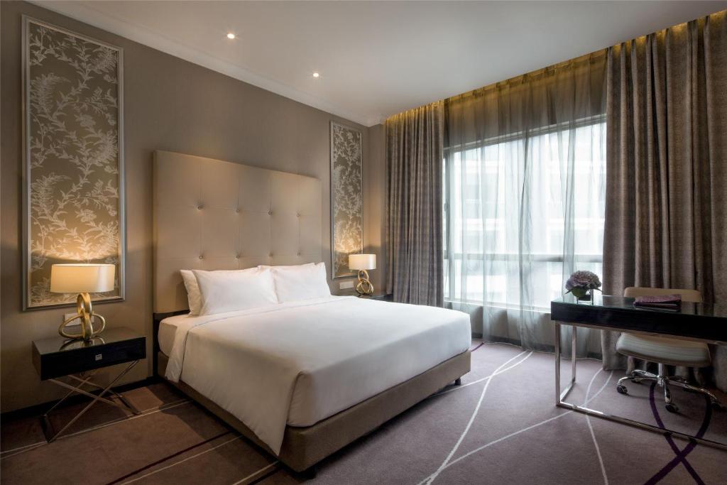 A polished room with a double bed, work desk and full-height window.