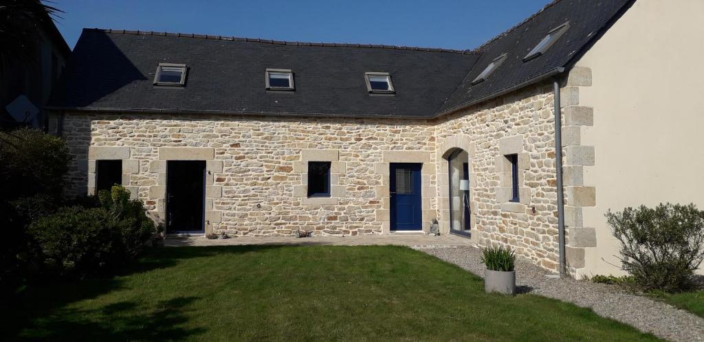 a stone house with a black roof at La fermette in Tréméoc