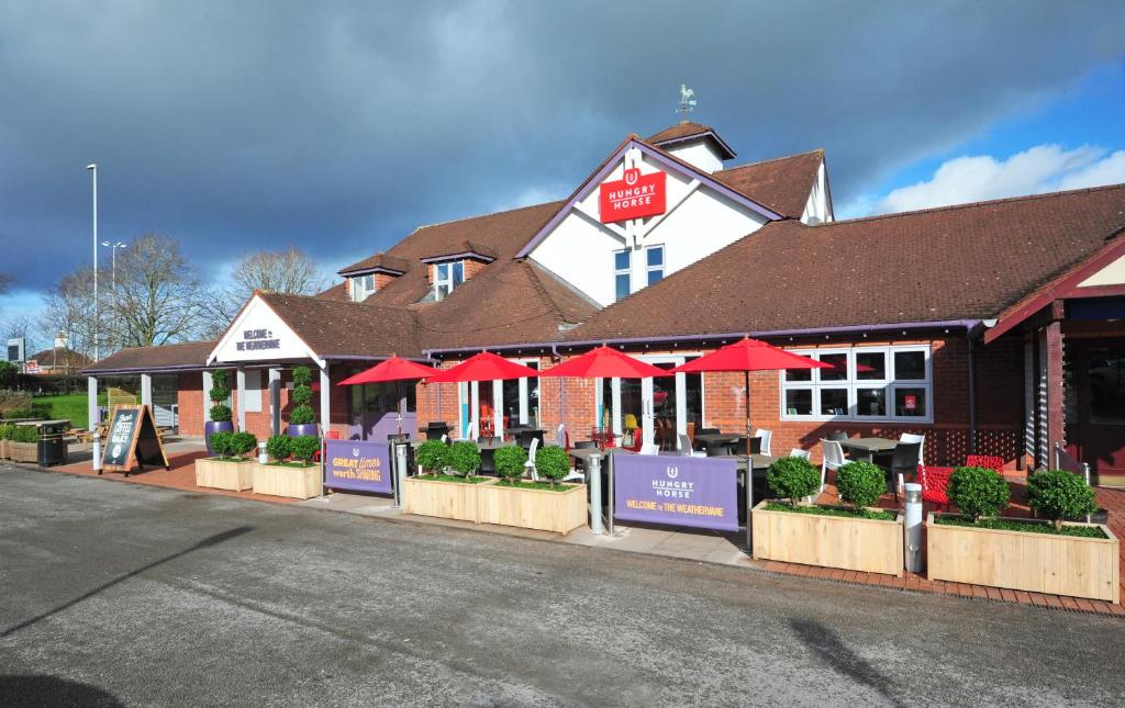 una tienda con sombrillas rojas frente a un edificio en Weathervane Hotel by Greene King Inns, en Stoke on Trent