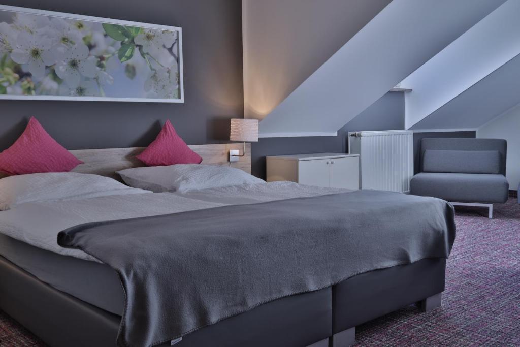 a bedroom with a large bed with pink pillows at Ilvericher Hof in Meerbusch