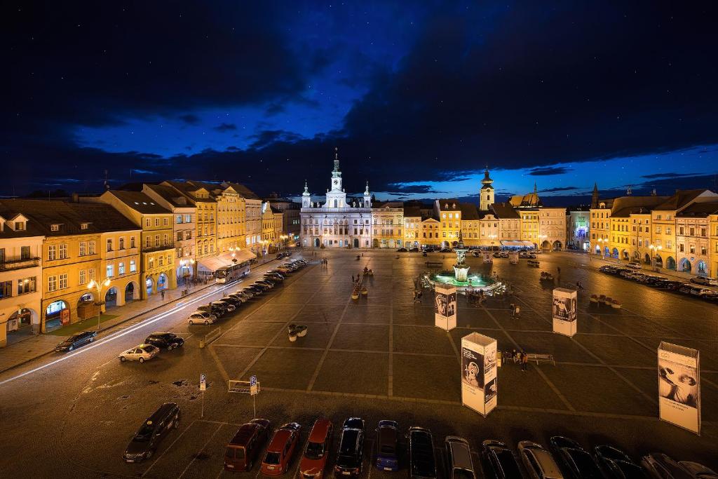 Una ciudad de noche con coches estacionados en un estacionamiento en Grandhotel Zvon, en České Budějovice