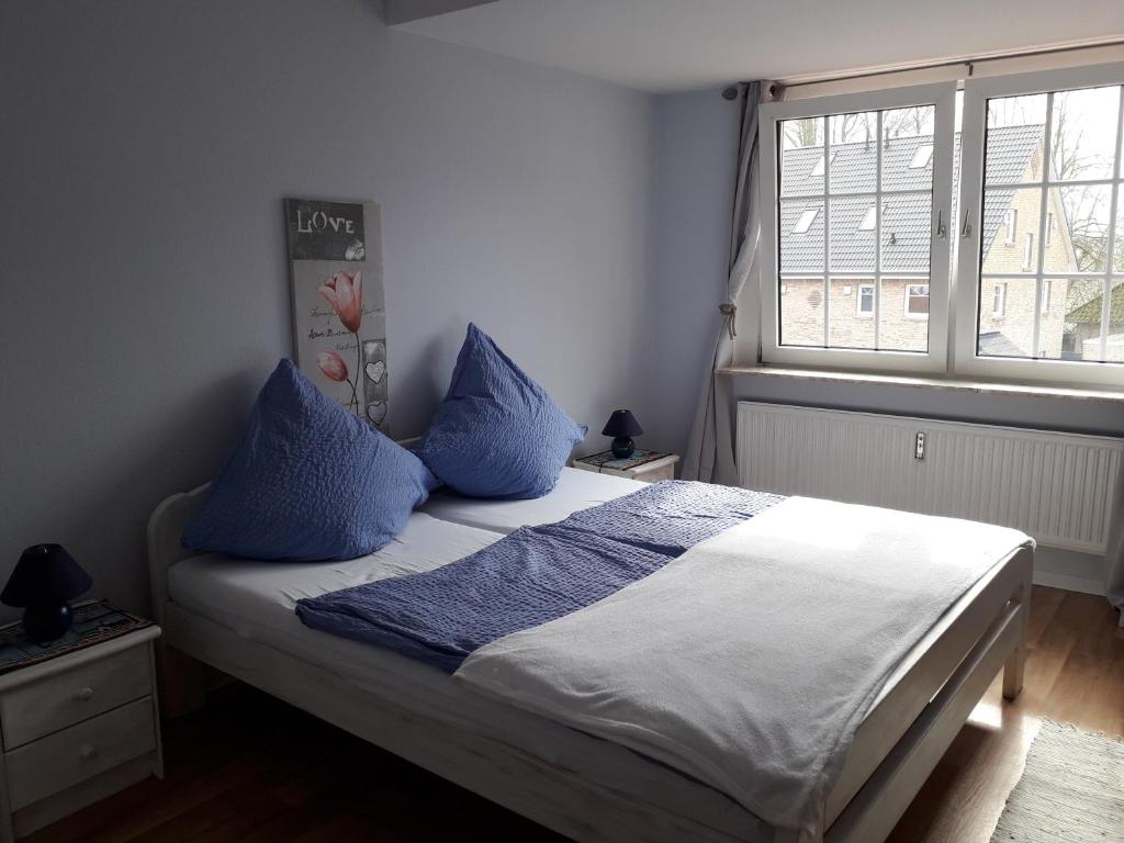 een slaapkamer met een bed met blauwe kussens en een raam bij Pension Norddeicher Straße in Norden