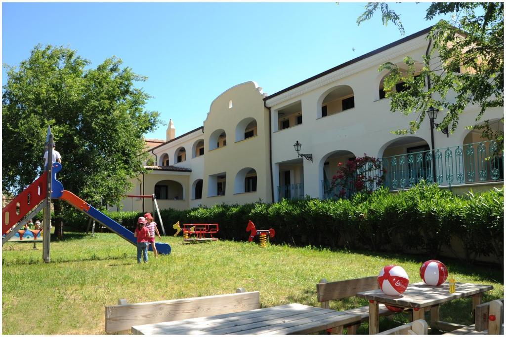 un grupo de niños jugando en un tobogán en el patio de un edificio en Residence Cala Liberotto, en Cala Liberotto