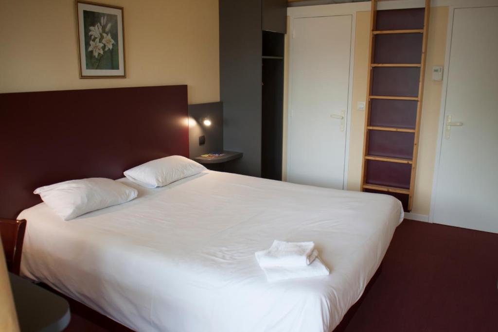 a bedroom with a large white bed with two towels on it at Mape hôtel in Dampierre-en-Burly