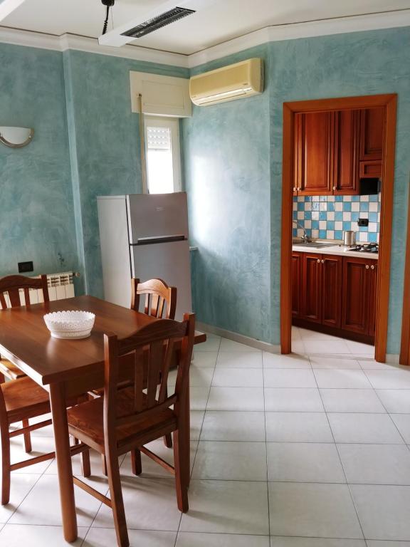 cocina con mesa, sillas y nevera en Webus Apartments, en Praia a Mare
