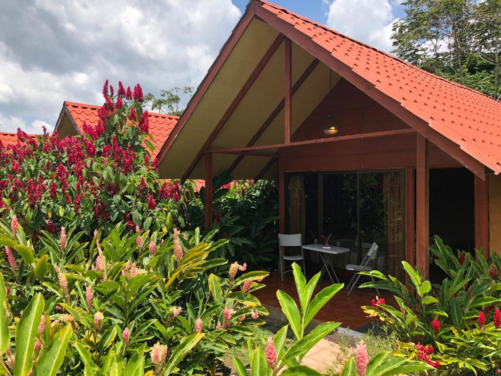 una casa con techo rojo y algunas flores en Hotel Villas Vista Arenal en Fortuna