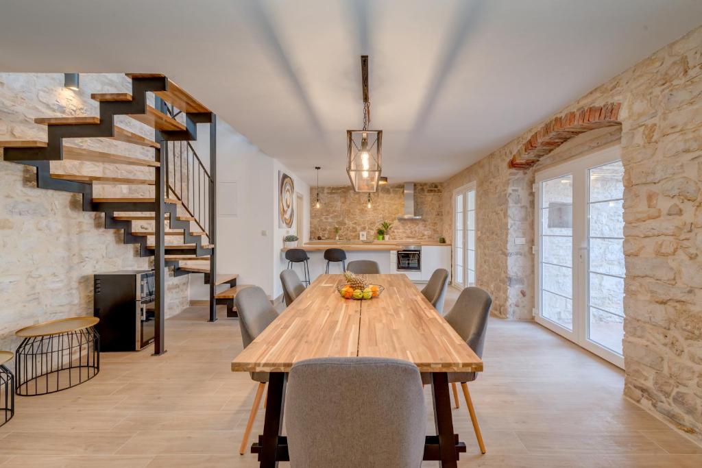 uma cozinha e sala de jantar com uma mesa de madeira e cadeiras em Holiday home Rocca em Supetar