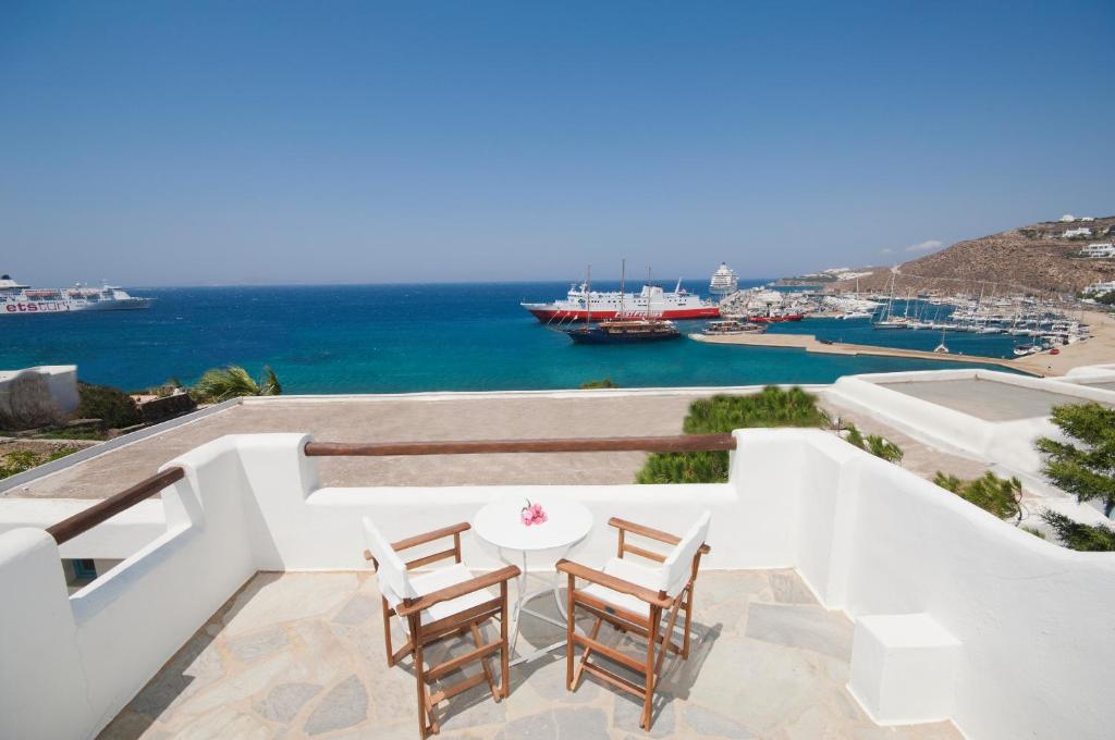 balcón con mesa, sillas y vistas al océano en Megas Rooms en Tourlos