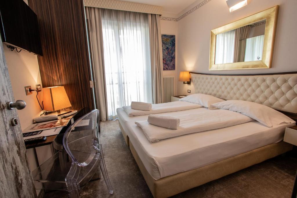 a hotel room with two beds and a window at Hotel Corona in Tirano