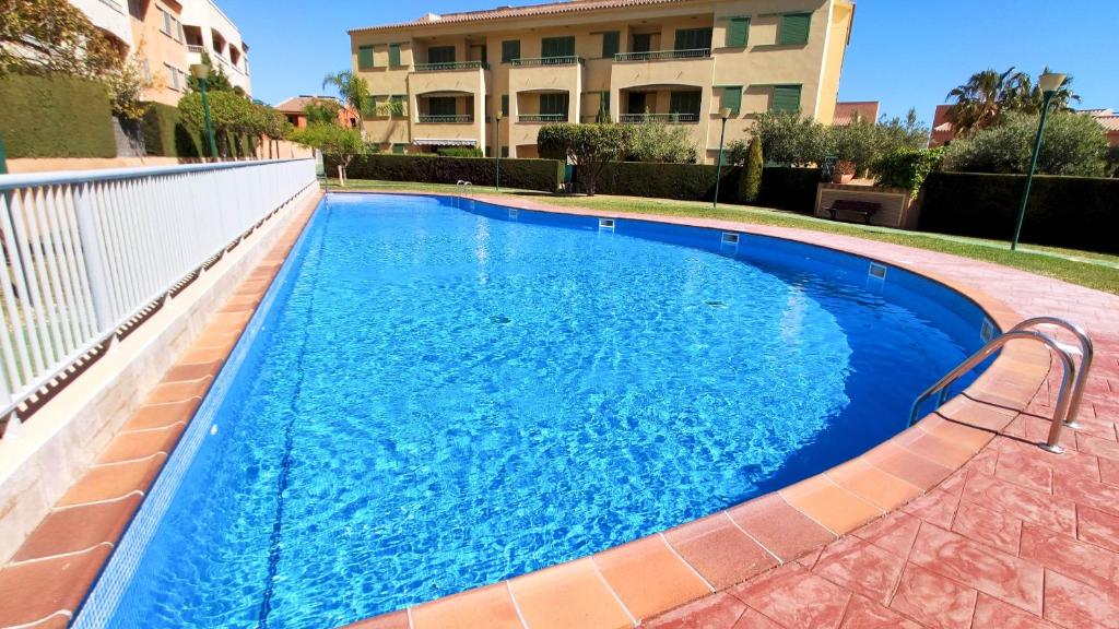 une piscine bleue avec banc à côté d'un bâtiment dans l'établissement Acogedor Apartamento Cerca del Mar MSJ75, à L'Ametlla de Mar