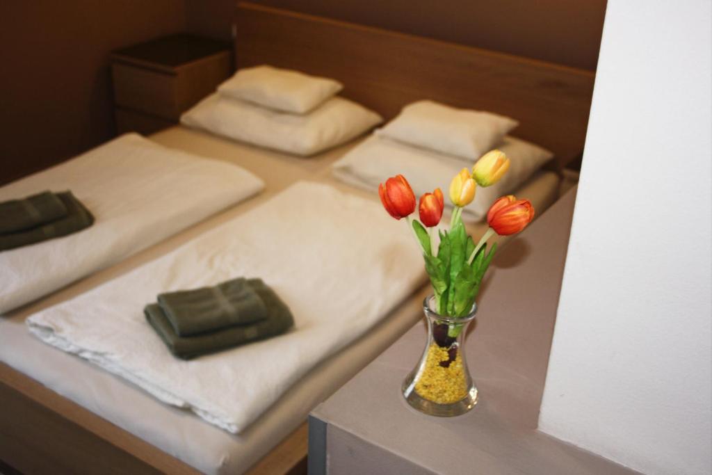 eine Vase mit Blumen auf einem Tisch mit 2 Betten in der Unterkunft Polus Pension in Sopron