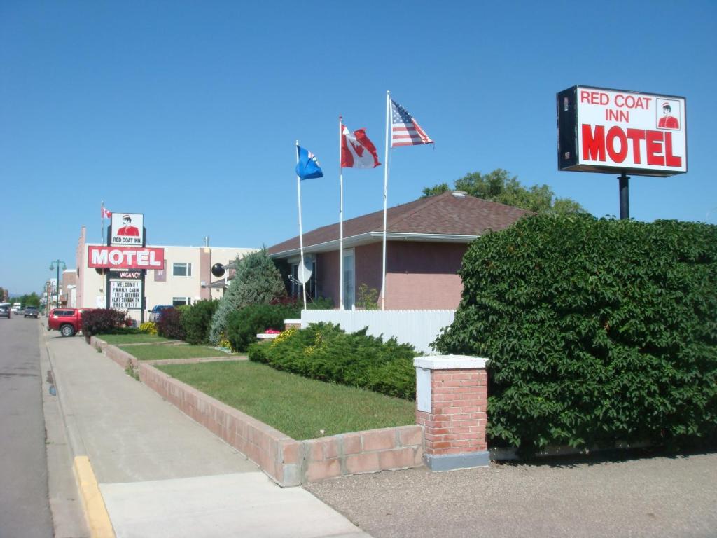 a motel with signs in front of a building at Red Coat Inn Motel in Fort Macleod