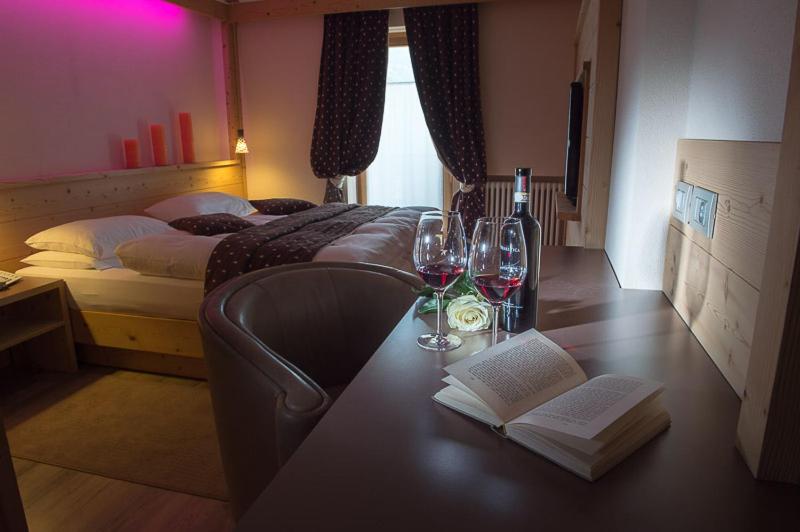 Un dormitorio con una mesa con copas de vino y una cama en Hotel Daniela, en Livigno