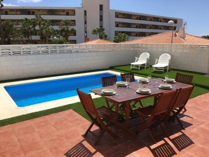 drewniany stół i krzesła przy basenie w obiekcie CHALET 84 con PISCINA PRIVADA w mieście Callao Salvaje