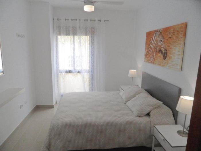 a white bedroom with a bed and a window at PLAYA SAN JUAN, Casa Vacacional CENTRICA in Playa de San Juan