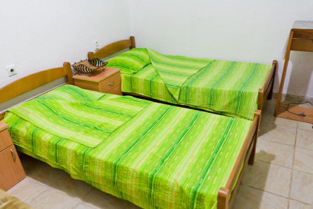 two beds with green sheets in a room at Rooms Sijak in Bar