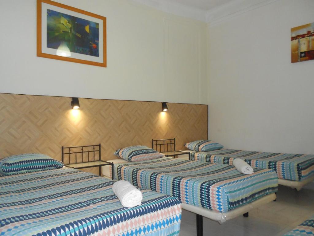 Habitación de hotel con 3 camas y una foto en la pared en Crescent Rooms, en Lisboa