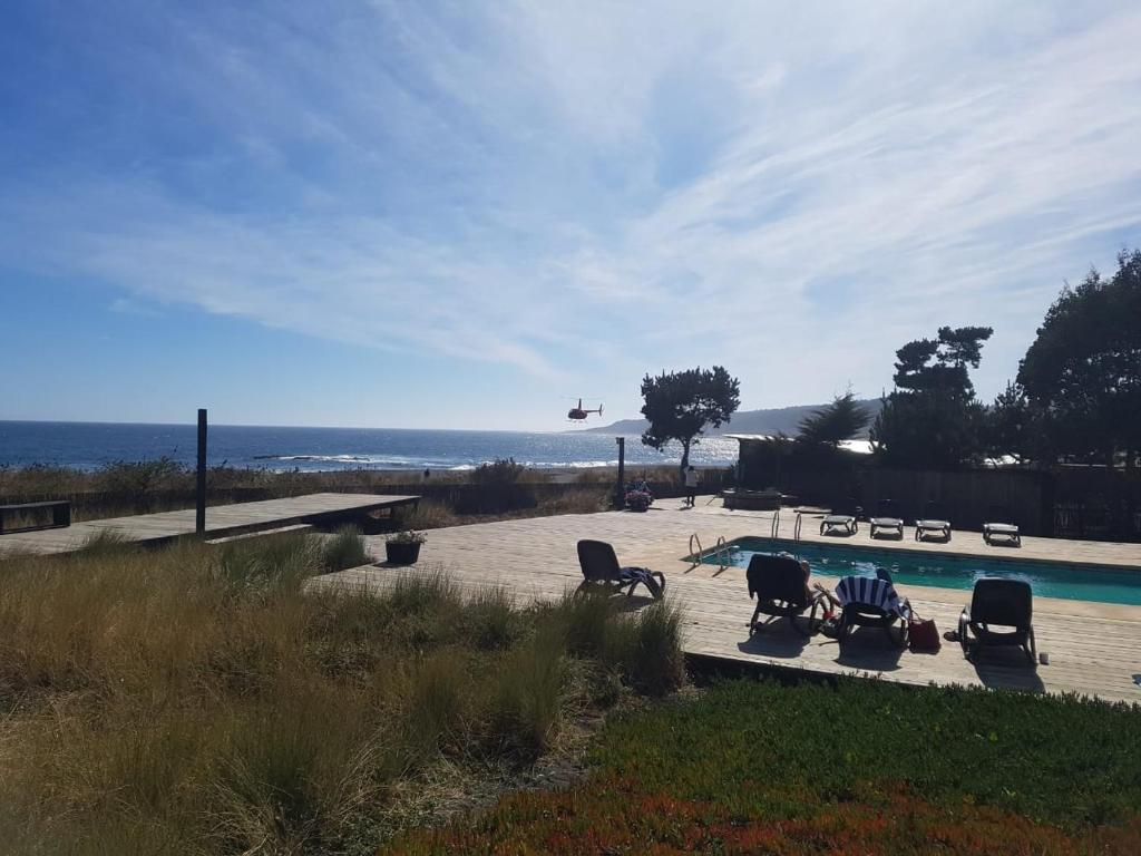 a helicopter flying over a swimming pool with chairs at Hotel Punta Sirena in Curanipe