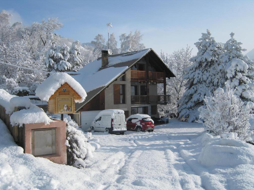 een huis bedekt met sneeuw met auto's geparkeerd buiten bij Le Petit Randonneur in Briançon