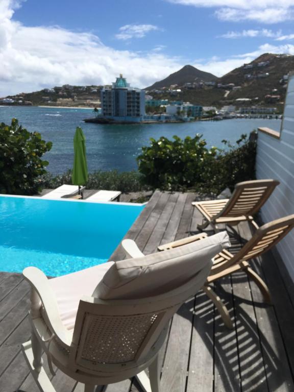 een terras met stoelen en een zwembad bij Villa CECILIA in Oyster Pond