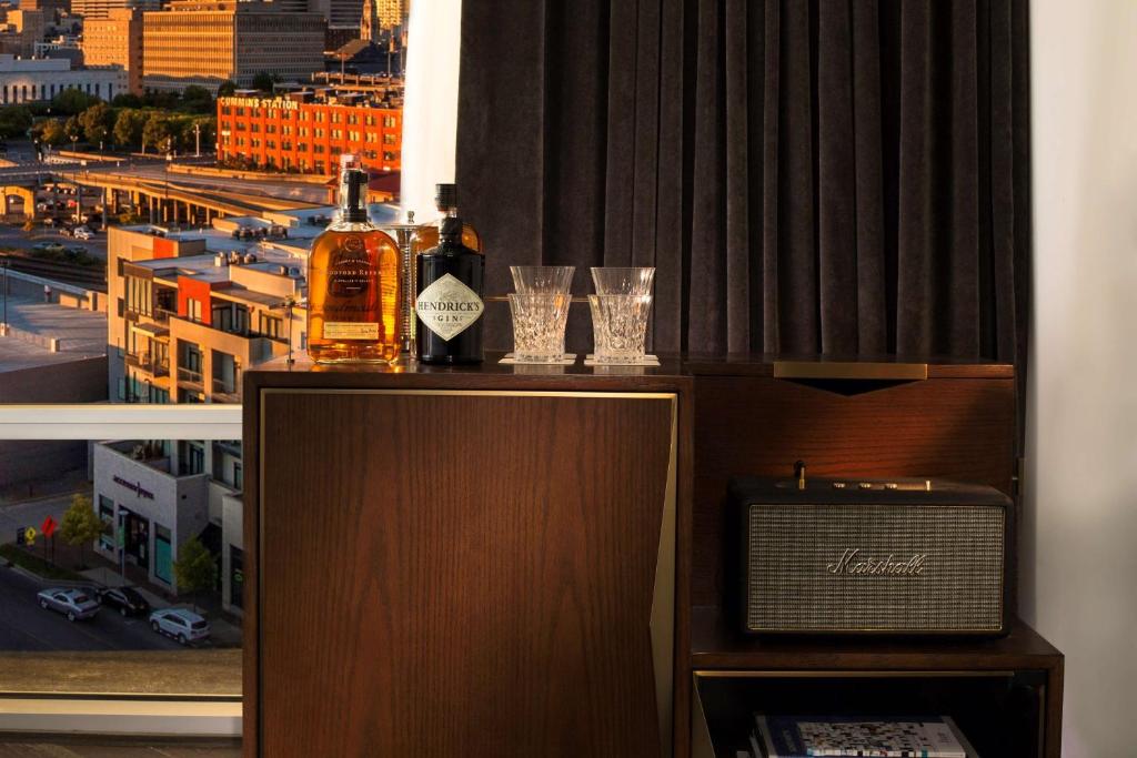 a bottle of alcohol sitting on top of a cabinet with glasses at Thompson Nashville, by Hyatt in Nashville