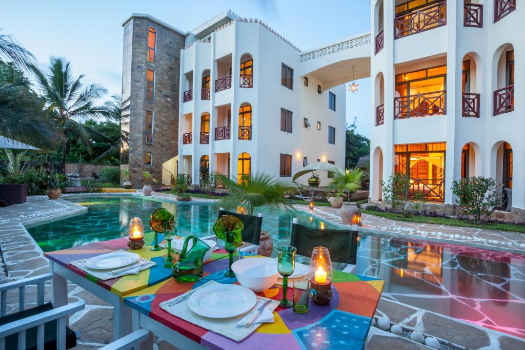 a villa with a pool and a table with plates on it at Amani Luxury Apartments in Diani Beach