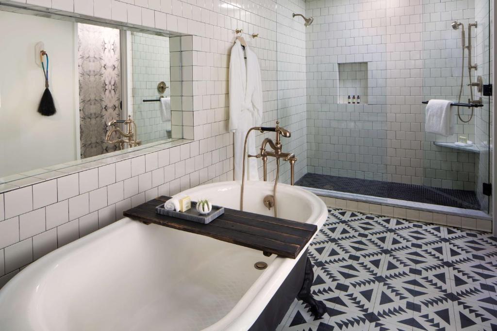 a white bathroom with a tub and a shower at Thompson Nashville, by Hyatt in Nashville