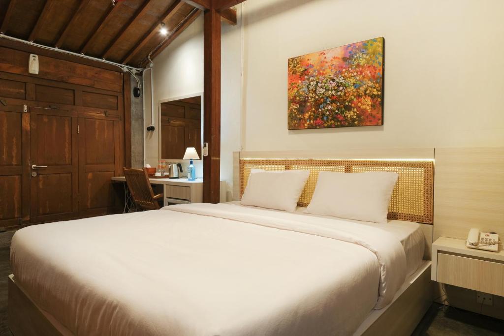 1 dormitorio con 1 cama y una pintura en la pared en Kampung Lawasan Heritage Cottage en Yogyakarta