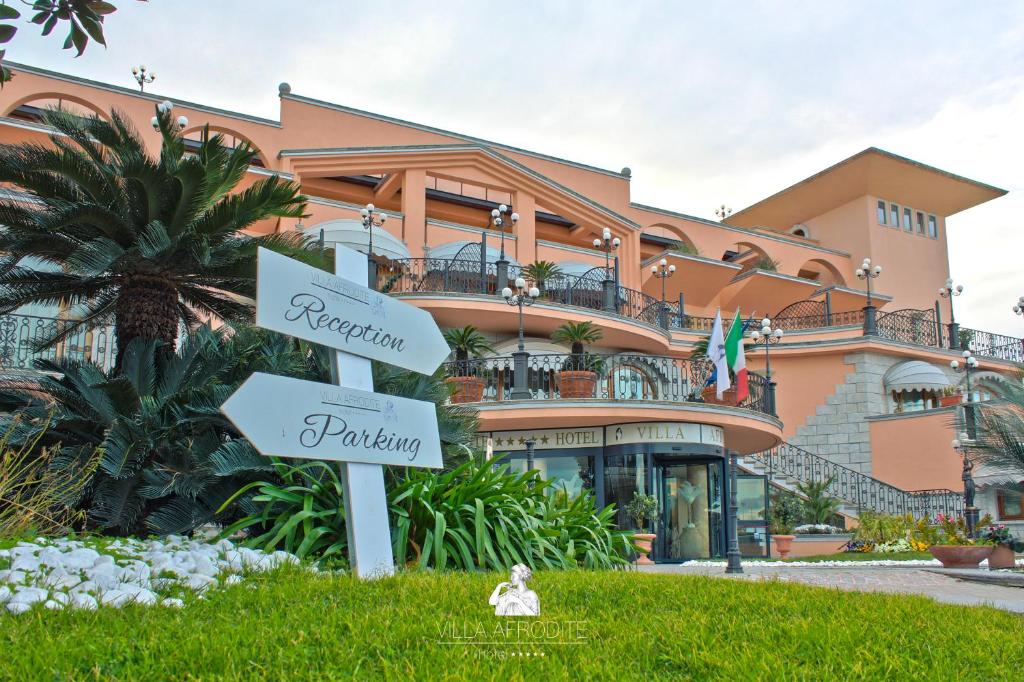 a sign in the grass in front of a building at Afrodite Boutique Hotel in Bovalino Marina