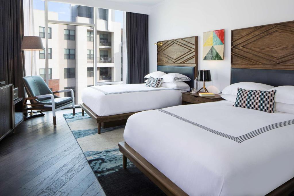 a hotel room with two beds and a chair at Thompson Nashville, by Hyatt in Nashville