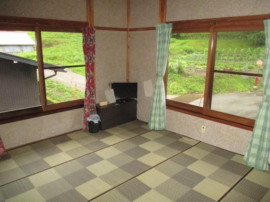 een lege kamer met twee ramen en uitzicht op een veld bij Minpaku TOMO 8 tatami room / Vacation STAY 3707 in Hida