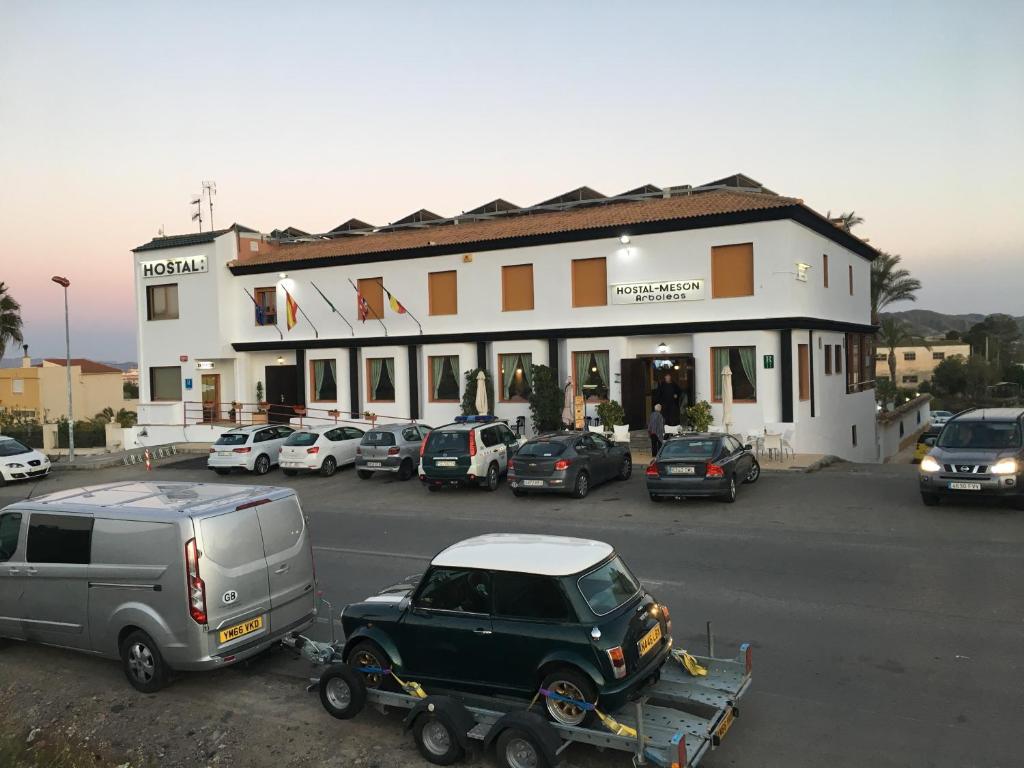 a parking lot with cars parked in front of a building at Hostal Mesón Arboleas in Arboleas