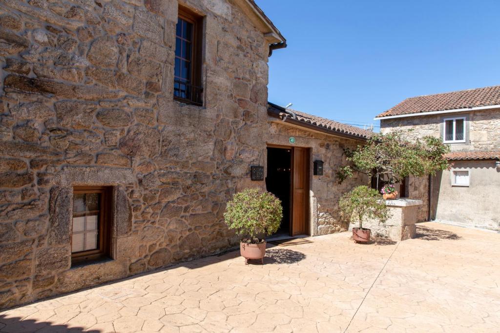 a stone building with two potted plants in front of it at Casa Rural as Bentinas in Milladoiro