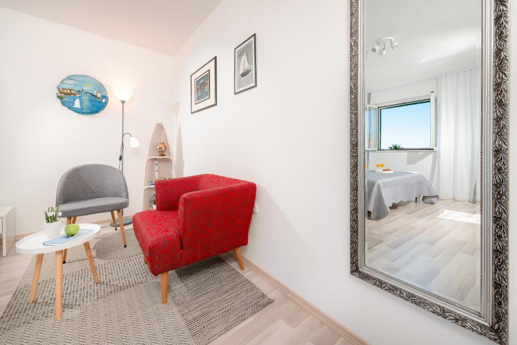 a living room with a red chair and a mirror at Apartment Adventure in Split