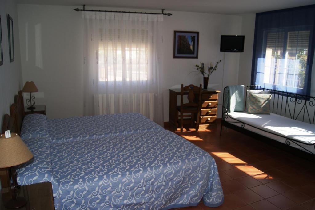 a bedroom with a bed and a couch and a window at Habitaciones Casa Rural El Sauce in Nohales