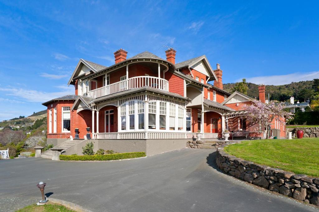 ein großes rotes Backsteinhaus mit Auffahrt in der Unterkunft St Leonards Lodge in Dunedin