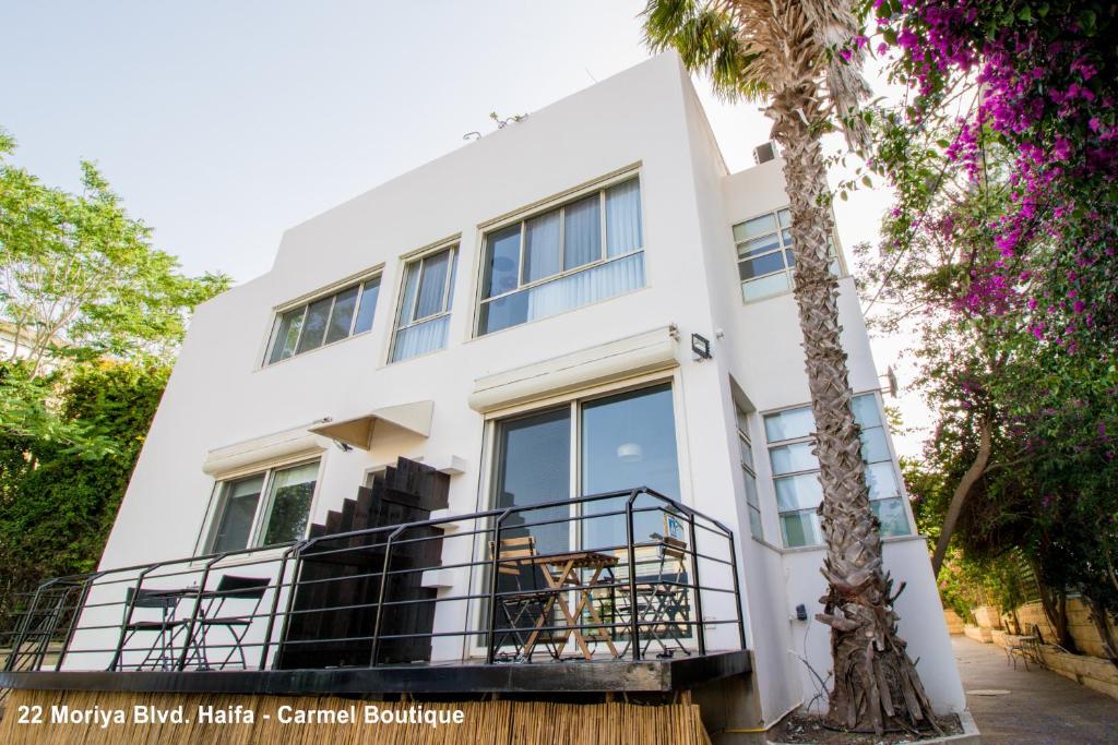 un bâtiment blanc avec un palmier en face dans l'établissement Carmel Boutique Apartments, à Haïfa