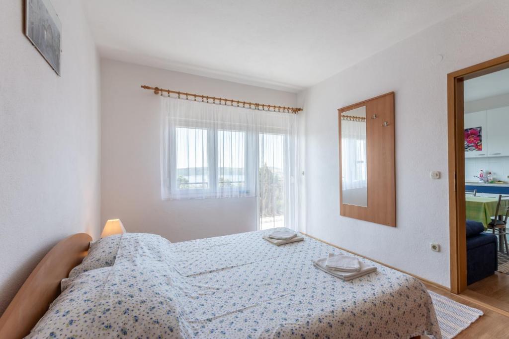 a white bedroom with a bed and a mirror at Apartments Mimi in Trogir