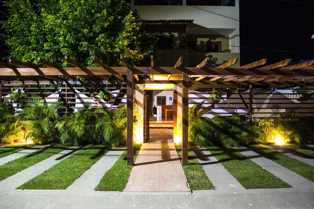 uma pérgola de madeira num jardim à noite em Pousada Casa Kuavá Experience em Maragogi