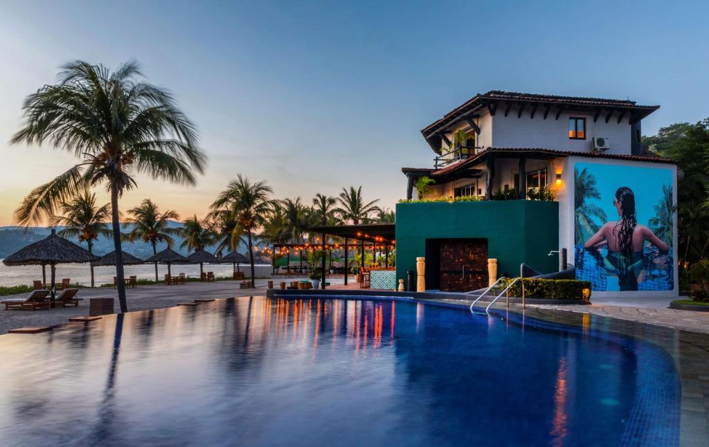 a hotel with a swimming pool in front of a building at Thompson Zihuatanejo, A Beach Resort, by Hyatt in Zihuatanejo