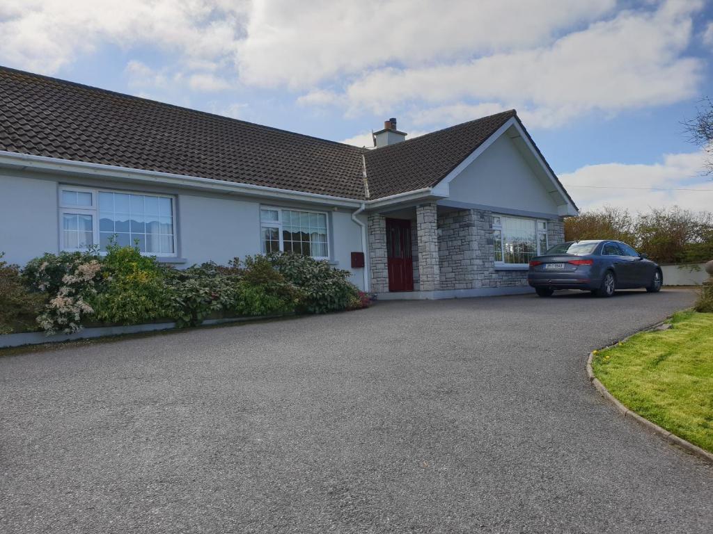 a white house with a car parked in the driveway at Glencora B&B in Skibbereen