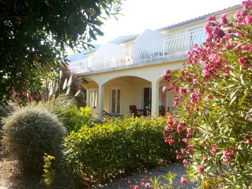 a white house with pink flowers in front of it at Apartman Dubravka 1 in Orebić