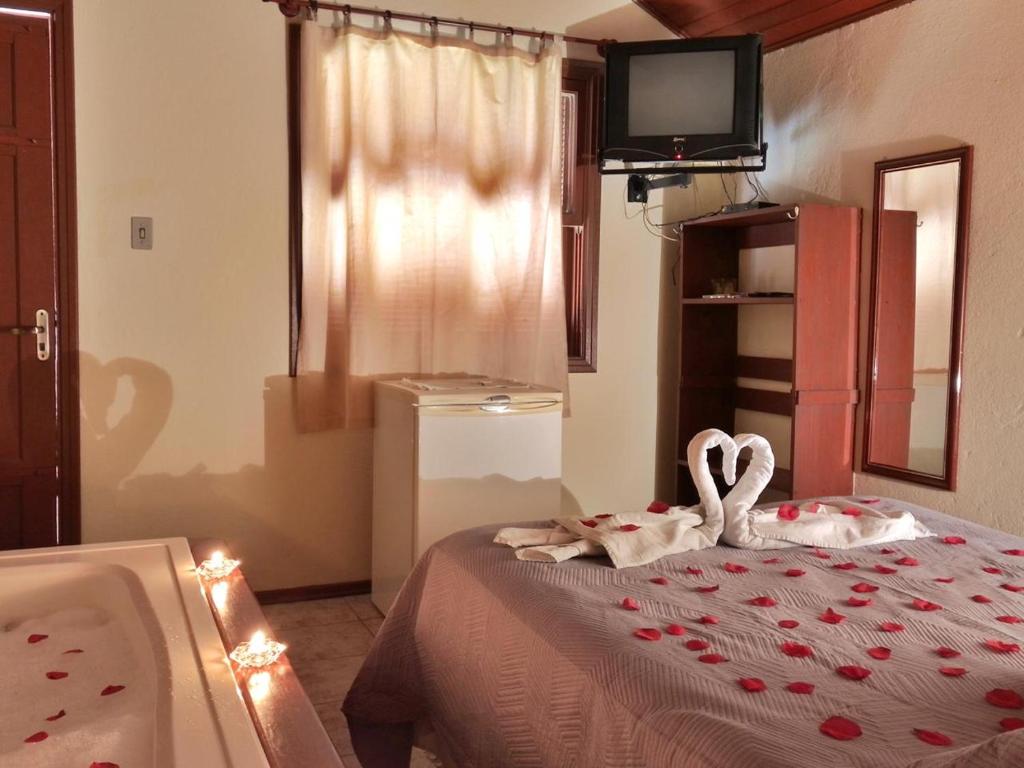um quarto com uma banheira e 2 cisnes numa cama em Chalés 4 Estações em Monte Verde