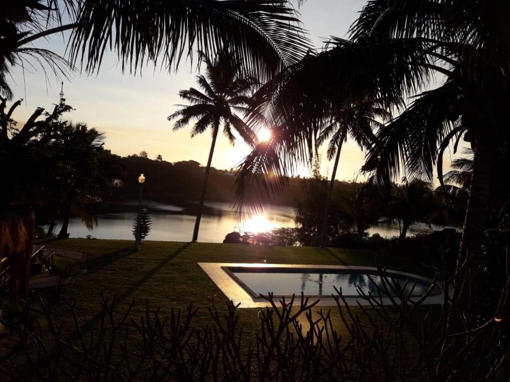 a sunset over a pond with palm trees and a body of water at Bilene Dream House 1 in Vila Praia Do Bilene